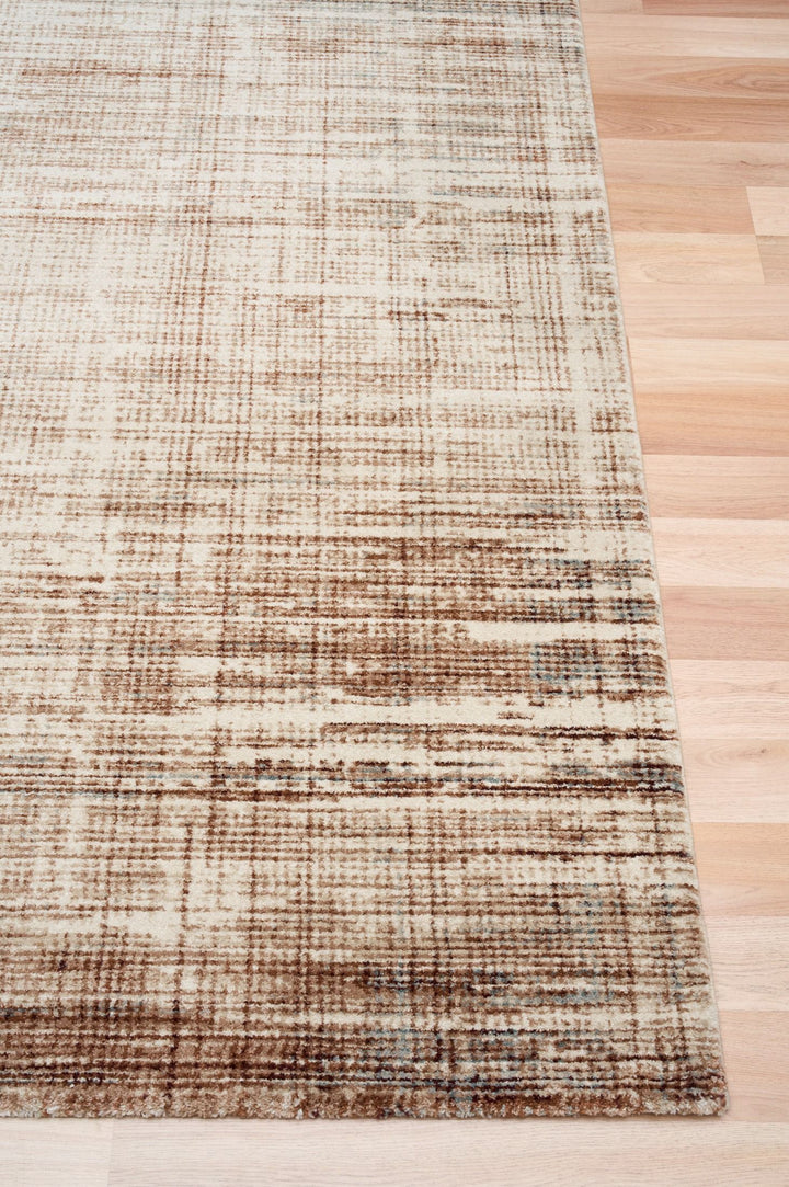 A brown patterned rug displayed on a wooden floor.