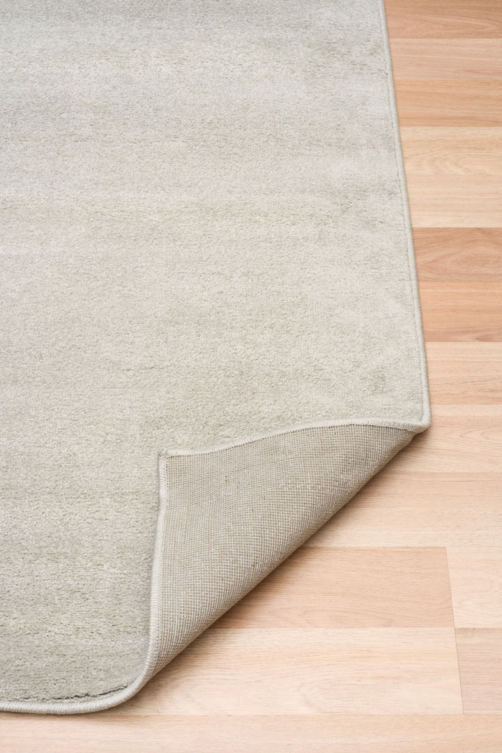 Beige rug corner folded showing backing.