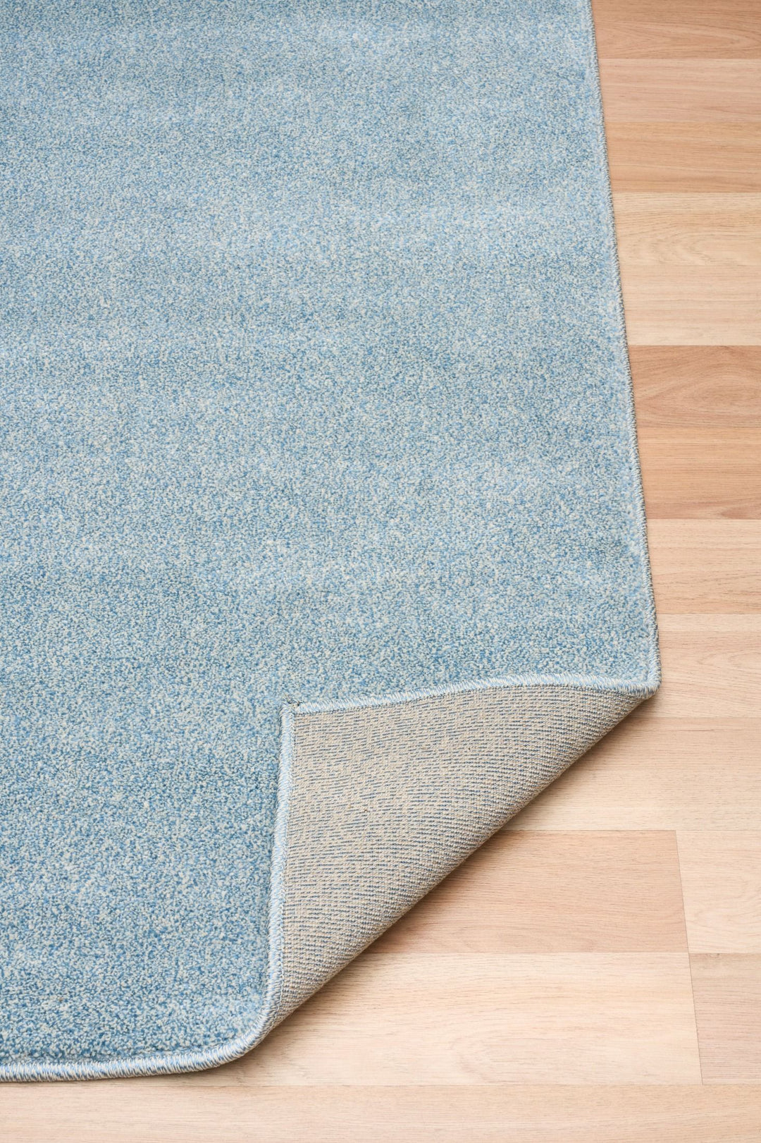 Light blue rug corner folded to show the underside texture.