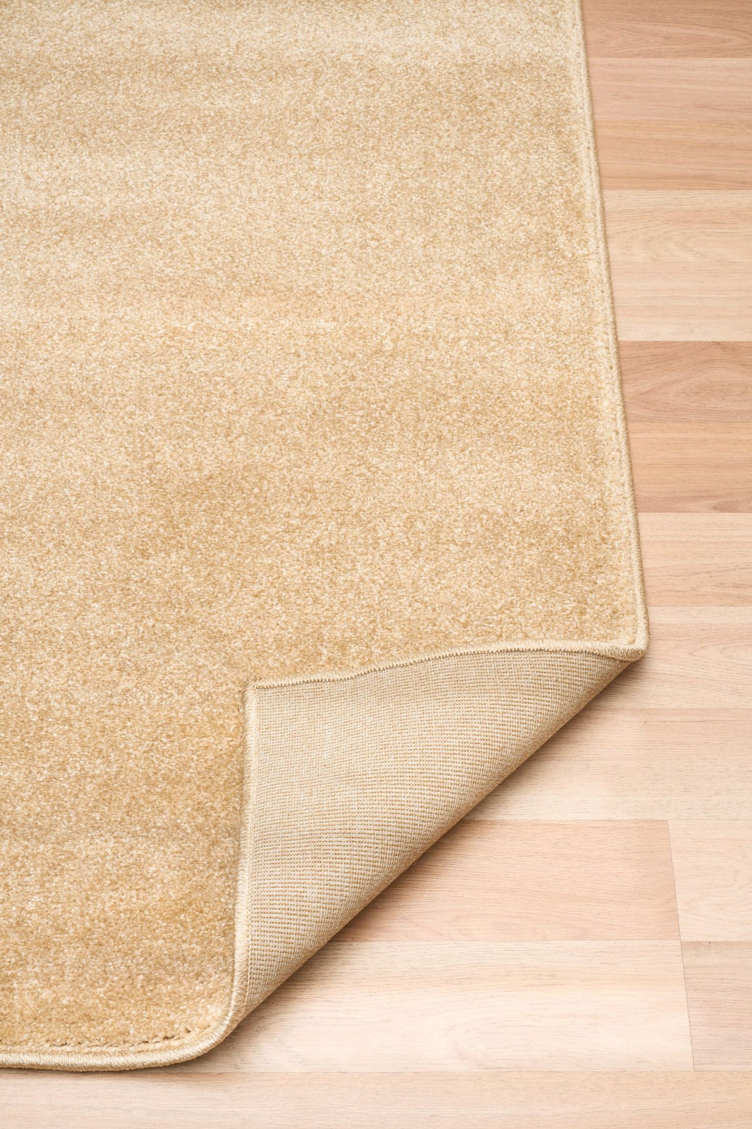 Beige rug with corner folded to show backing.