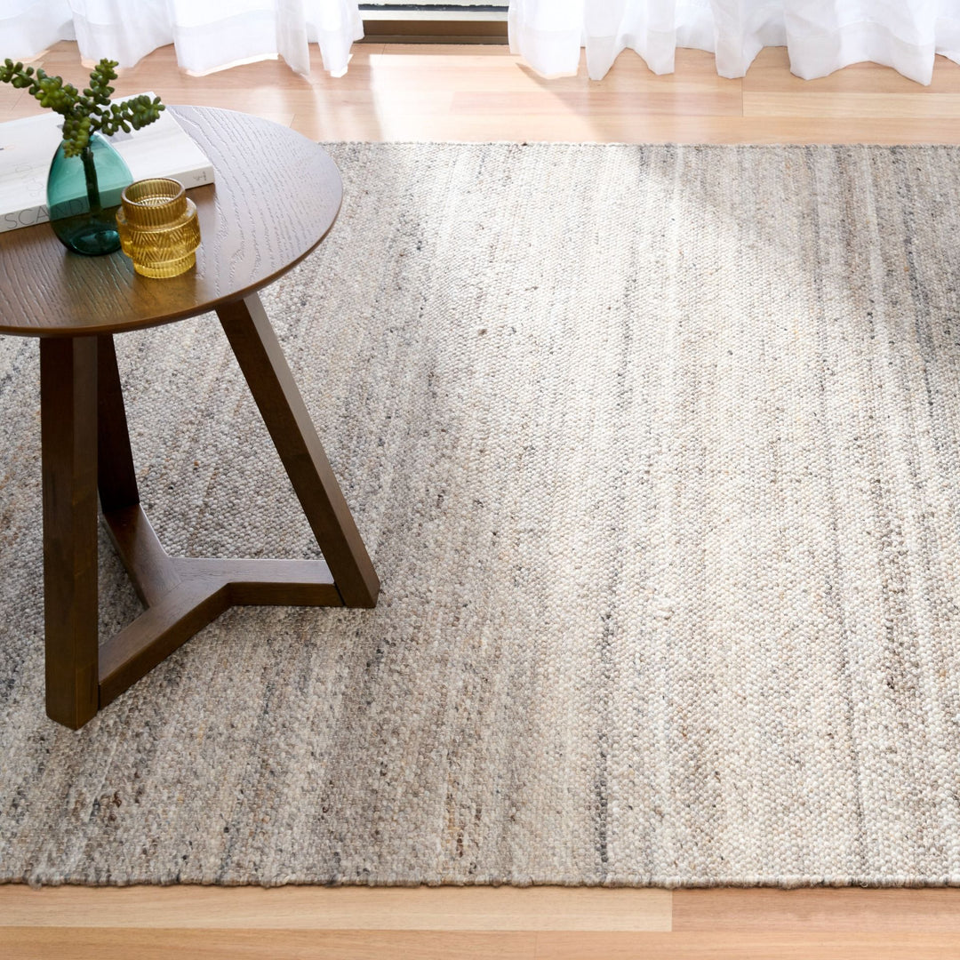 Square crop of dark grey rug in a bright room setting.