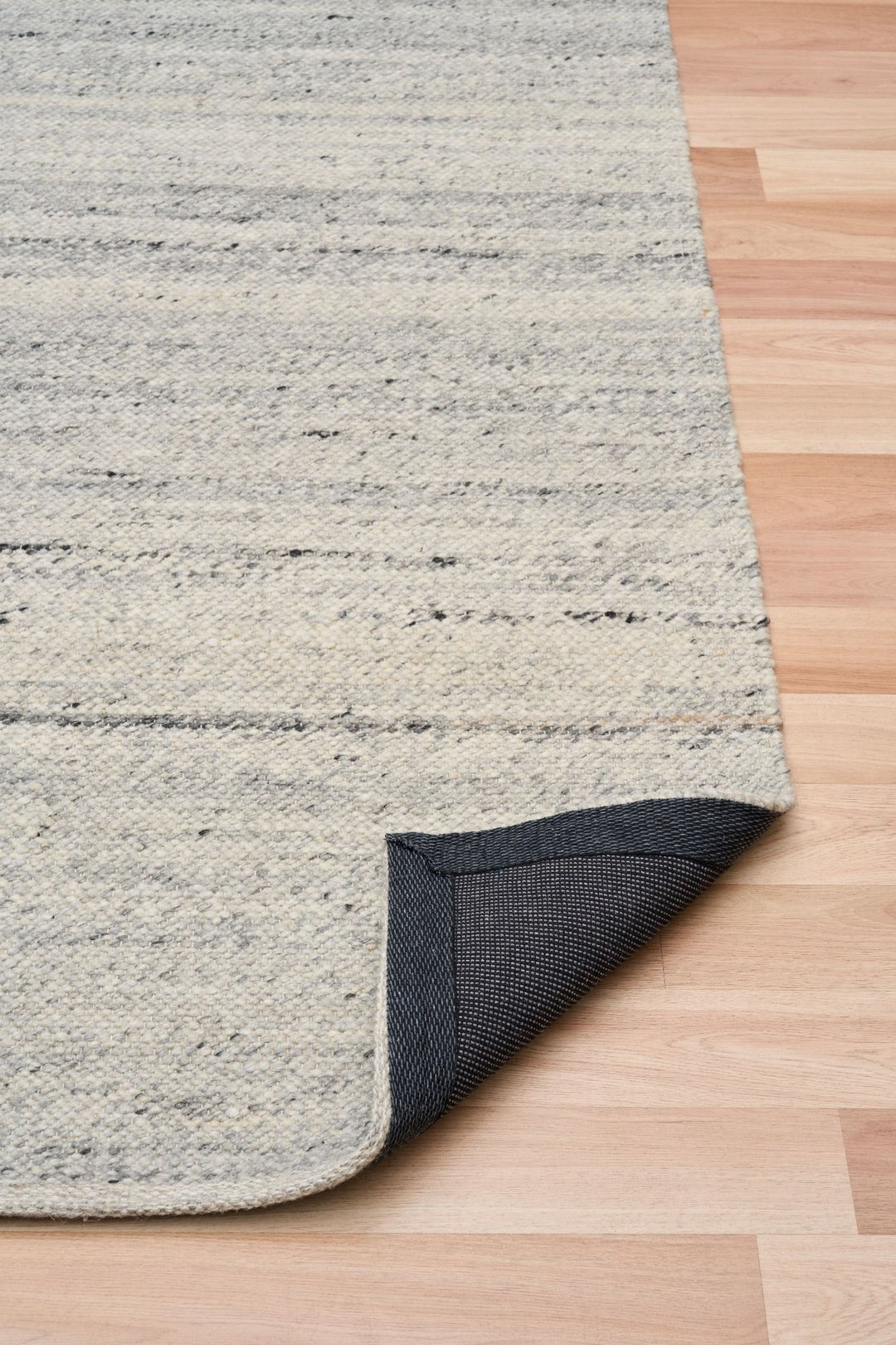 Angled view of silver rug corner highlighting detailed weave.