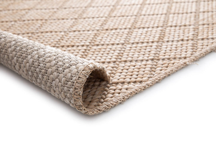 Beige woven rug with raised diamond lattice, rolled corner, stitched edge, and backing.