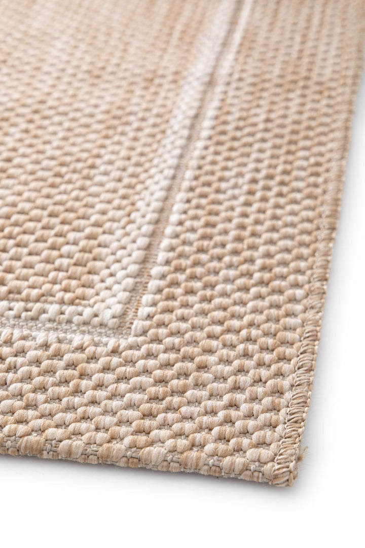 Close-up detail of a beige woven rug showing the basketweave texture, stitched border, and subtle framed pattern on a white background.