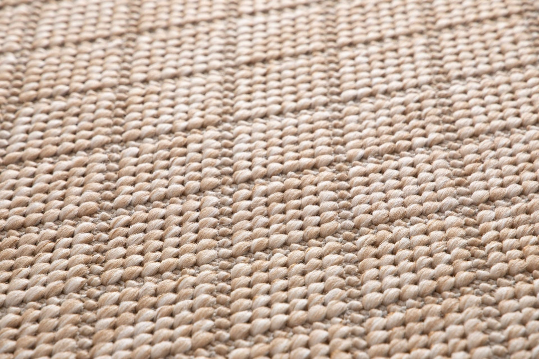 Close-up of a beige woven rug highlighting its diamond lattice pattern and chunky looped fibers.
