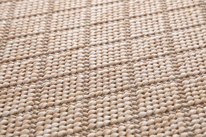 Close-up of a beige woven rug highlighting its diamond lattice pattern and chunky looped fibers.