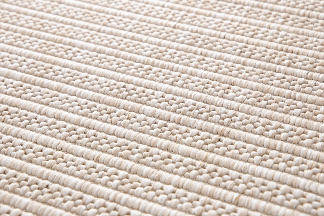 Close-up of a beige woven rug highlighting its diamond lattice pattern and chunky looped fibers.