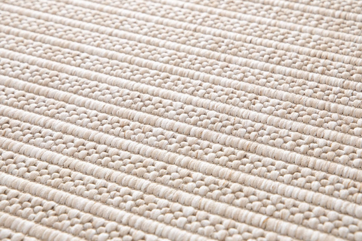 Close-up of a beige woven rug highlighting its diamond lattice pattern and chunky looped fibers.