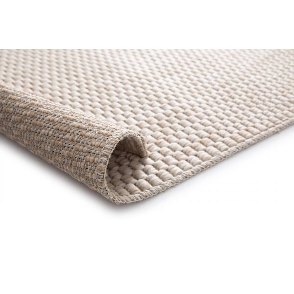 Flat woven rug in a soft taupe color with a subtle checkered texture, creating a minimalist and neutral aesthetic.