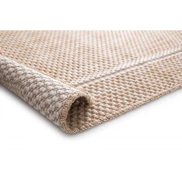 Close-up of a beige woven rug with chunky basketweave texture, bound edge, and a rolled corner on a white background.