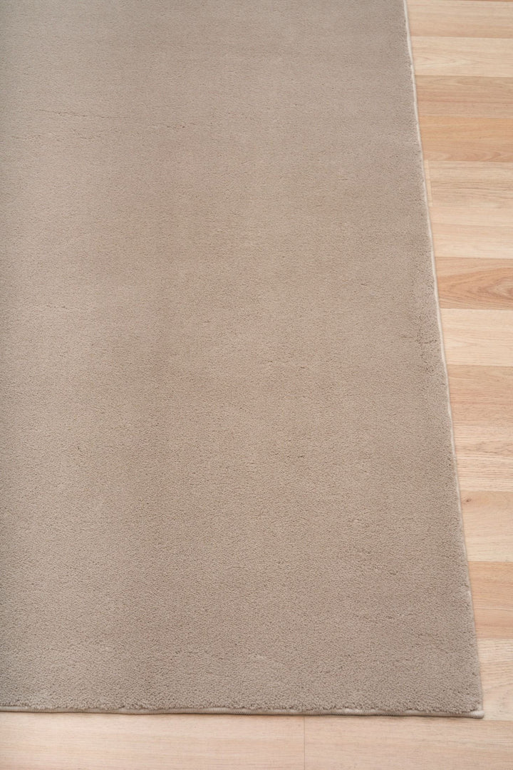 Close-up of a clay rug corner placed on a wooden floor.