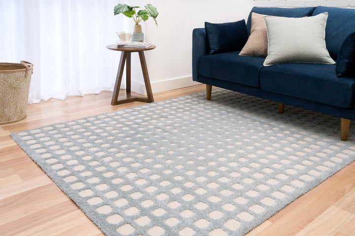 Blue and white rug styled in living room with navy sofa.