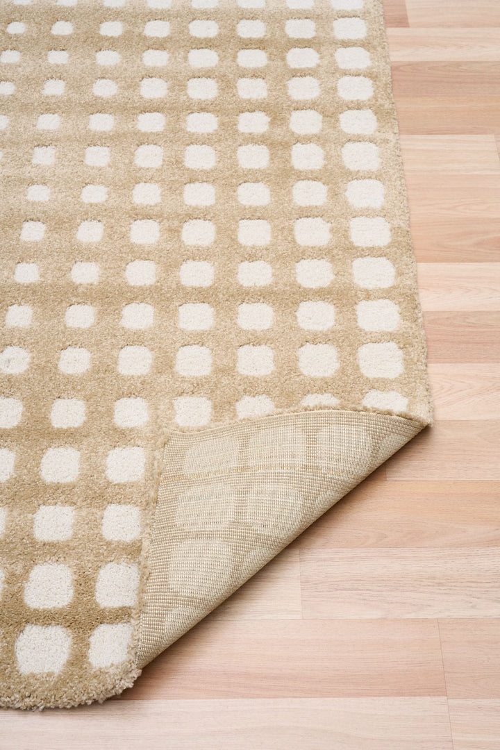Folded corner of beige rug showing backing.