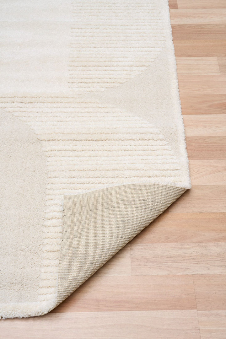 Cream rug corner lifted to show backing detail.