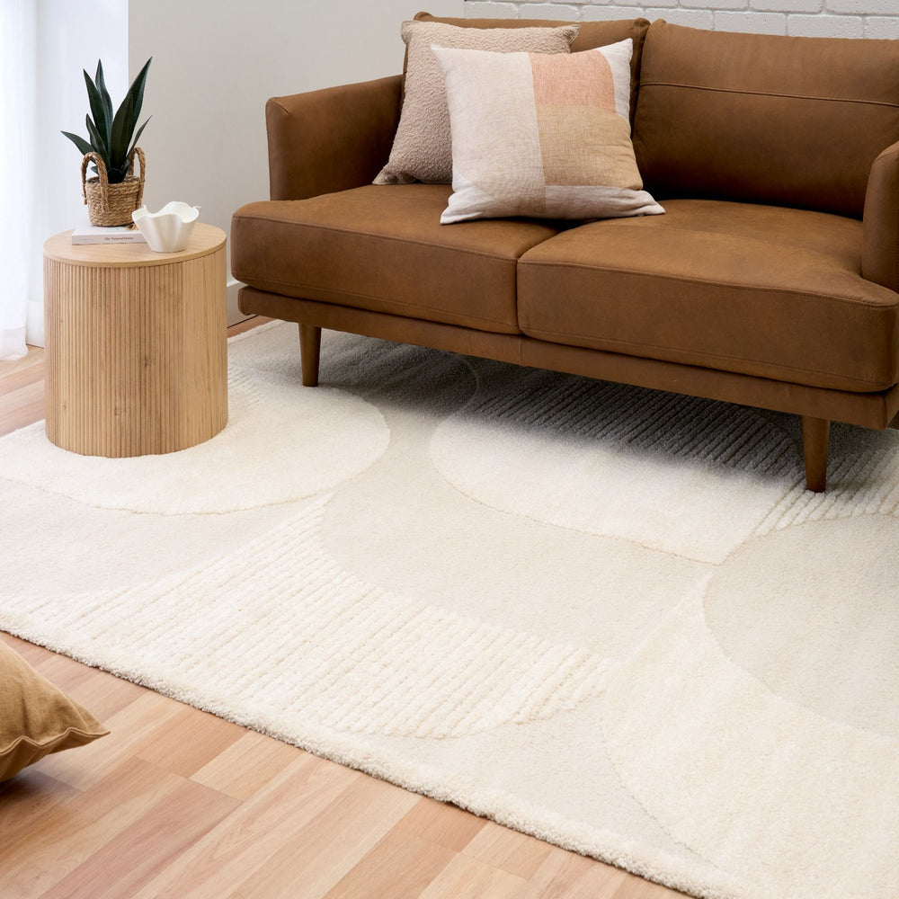 Cream rug styled with modern brown sofa and table.