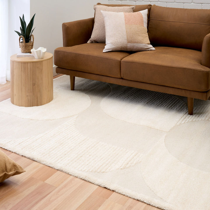 Cream rug styled with modern brown sofa and table.