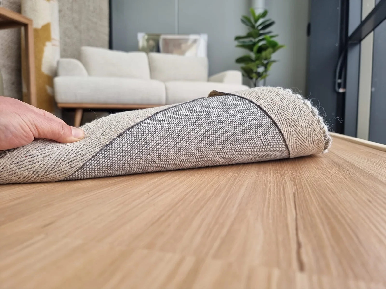 Wool rug lifted to show cotton backing on timber flooring