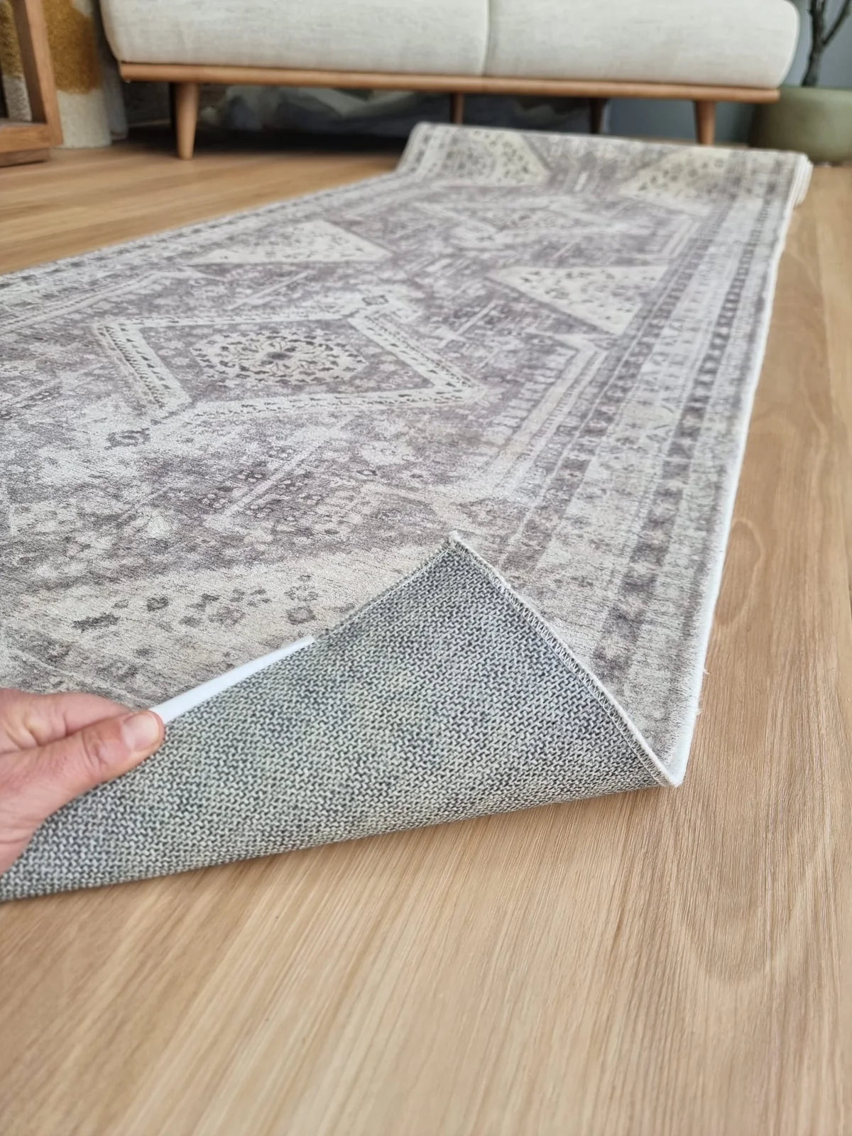 Machine-washable rug lifted to show non-slip backing on timber flooring