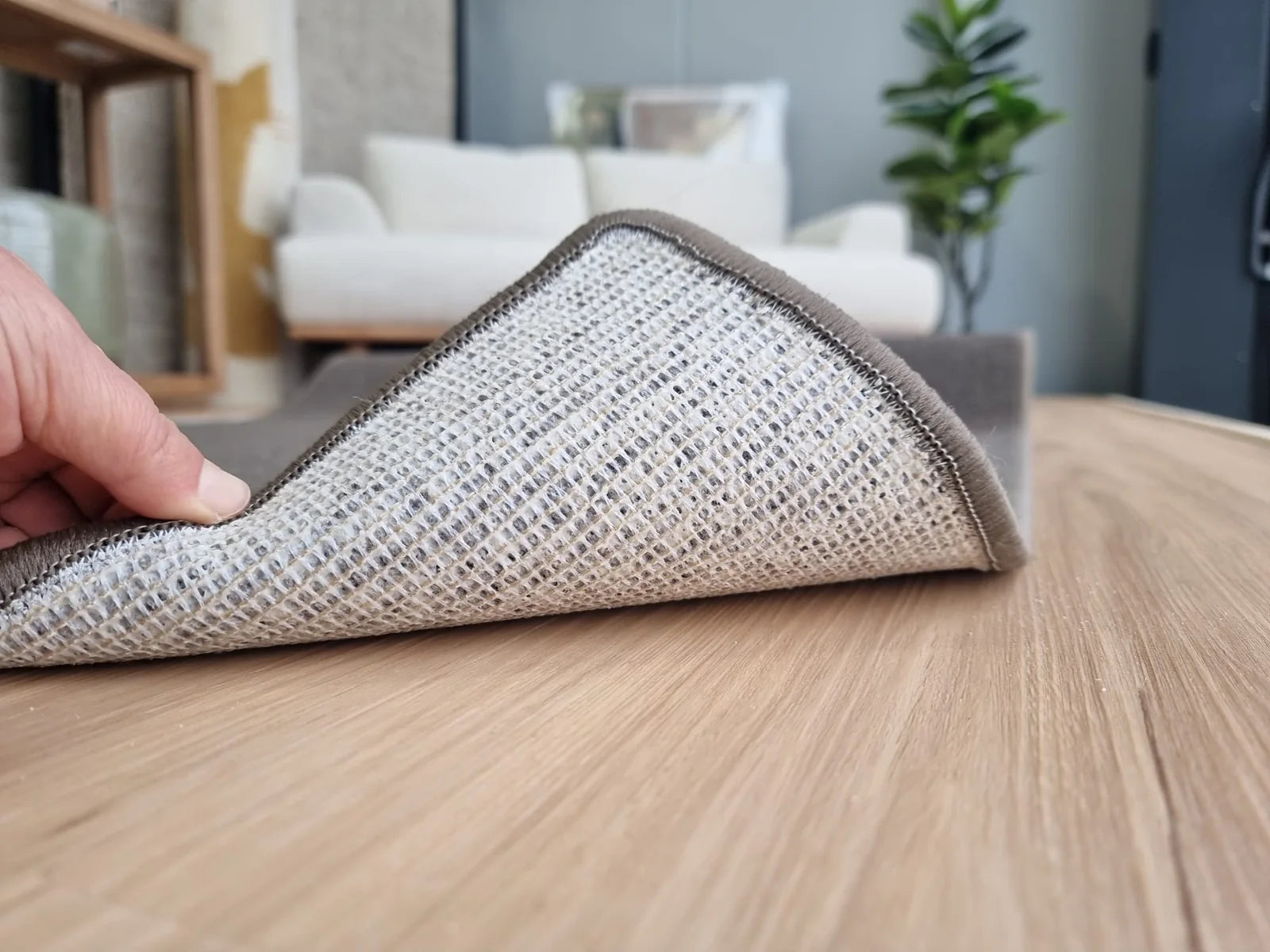 Nylon action rug backing lifted on timber flooring, showing the woven secondary backing