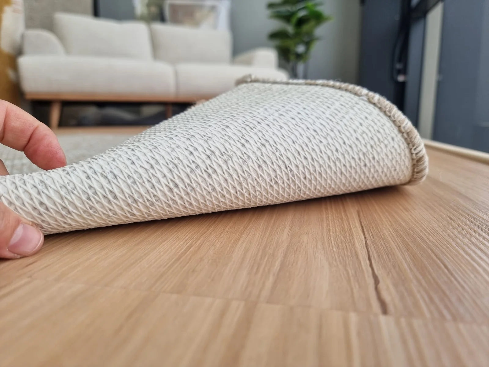 Rubber latex rug backing lifted on timber flooring, showing the textured grip layer